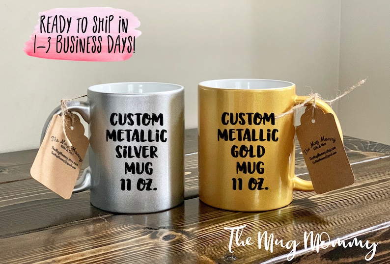 May include: Two metallic mugs, one silver and one gold, each with a handle and a tag. The silver mug reads "CUSTOM METALLIC SILVER MUG 11 OZ." The gold mug reads "CUSTOM METALLIC GOLD MUG 11 OZ."