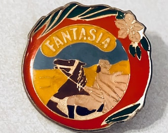 May include: A round enamel pin with the word "FANTASIA" in gold lettering. The pin features a horse and rider scene in a circular design with red, yellow, blue, and green accents. A floral design is on the top right.