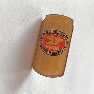 May include: A tan-colored pin shaped like a beer can. The pin features a red and white circular logo with the text "33 export" and the words "Bière" and "Beer" in a circular pattern. The pin also has the text "PRE DE LUP".