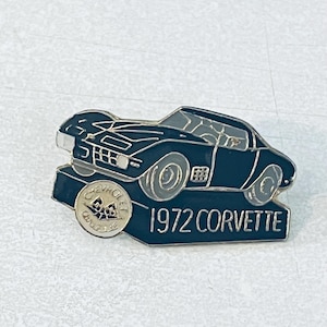 May include: A black and silver 1972 Corvette pin. The pin features a detailed depiction of the car's silhouette, with the words "1972 Corvette" and the Chevrolet logo. The pin is made of metal.