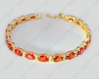May include: A gold bracelet with a row of oval-shaped red gemstones and small clear gemstones.