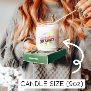 May include: A white candle in a glass jar with a yellow and pink label that says "Kizzubel Designs". The candle is 9 ounces and is sitting on a green box with matches.