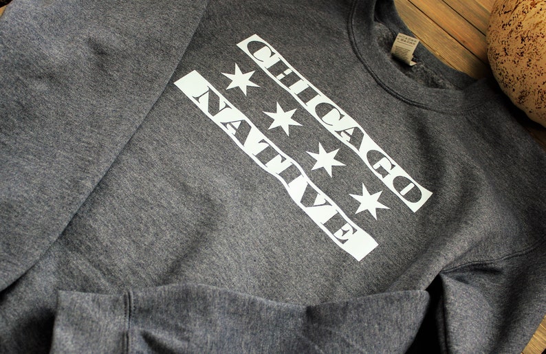 May include: A gray sweatshirt with a white graphic design featuring the words "CHICAGO NATIVE" and four white stars.