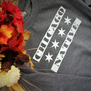 May include: Gray sweatshirt with white text that reads "CHICAGO NATIVE" with four white stars.