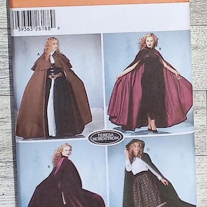 May include: A Simplicity sewing pattern envelope 5794 for capes in sizes XS, S, M, and L. The front displays four illustrations of capes in brown, black, and dark red, featuring various lengths, hoods, and closures, designed by Teresa Nordstrom.