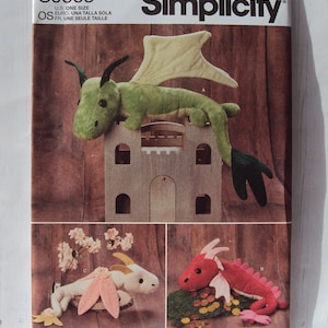 May include: Simplicity sewing pattern number S9363 for making three plush dragon toys. The pattern includes instructions for a green dragon, a pink dragon, and a white dragon with pink wings. The pattern is for one size.