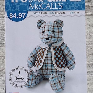 May include: A McCall's sewing pattern for a teddy bear. The bear is made of blue and brown plaid fabric and wears a dotted vest. The pattern includes the text "IT'S Sew SIMPLE" and "made with love in the U.S.A."