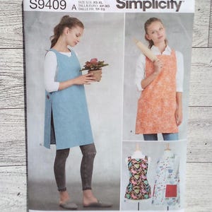 May include: Simplicity sewing pattern S9409 featuring aprons. The pattern includes multiple apron designs, with images of the finished products. The pattern is designed and printed in the USA. The size range is XS-XL.