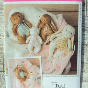 May include: A Simplicity sewing pattern for making stuffed animals. The pattern includes instructions for making a bear, a bunny, and a blanket. The pattern is designed by Tati.