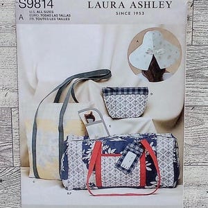 May include: A Simplicity sewing pattern envelope S9814 for Laura Ashley accessories. The cover displays a tote bag, a zippered pouch, a small case, and a duffel bag with red straps, plus a wide-brimmed hat. The patterns feature floral and plaid prints.