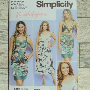 May include: Simplicity sewing pattern S9729 Madalynne for a slip dress with lace trim. The pattern includes three different styles: a short slip dress, a midi slip dress, and a bralette. The pattern is easy to sew and includes a QR code for a sew-along tutorial by Maddie Kulig.
