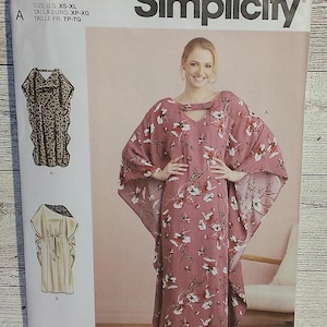 May include: A sewing pattern for a long, flowing dress with a keyhole neckline. The pattern is from Simplicity and is for sizes XS-XL. The dress is shown in two different fabrics, one with a leopard print and the other with a floral print.
