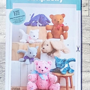 May include: A Simplicity sewing pattern envelope labeled CS9360 featuring illustrations of various stuffed animals including teddy bears, cats, and dogs in different colors and fabrics, with a blue header and a small scissor icon on the right side.