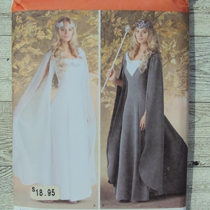 May include: Simplicity sewing pattern number 1551 KK for a long, flowing gown with a cape. The pattern includes two versions: one in white and one in gray. The pattern is for sizes 8-14, 34-40, 36-42.