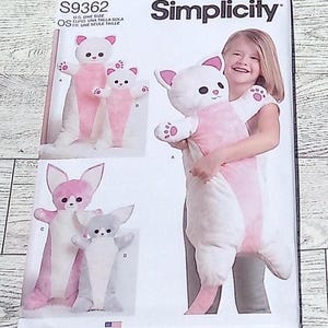 May include: Simplicity sewing pattern S9362 featuring a plush cat costume. The pattern includes instructions for creating a white and pink cat costume, with a child modeling the finished product. The pattern is designed and printed in the USA.