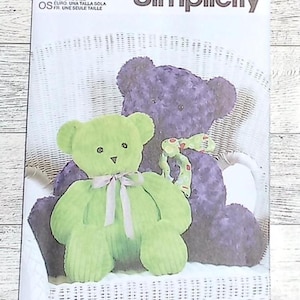 May include: Simplicity sewing pattern featuring two plush teddy bears. One bear is lime green with a pink bow, and the other is purple with a patterned bow. The pattern is labeled S9307 and includes the text "U.S. ONE SIZE".