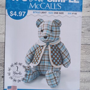 May include: A McCall's sewing pattern envelope for a stuffed bear, labeled IT'S SEW SIMPLE, style L9547. The image shows a bear made of blue and brown plaid fabric, wearing a brown vest with blue polka dots and a white lace-trimmed collar.