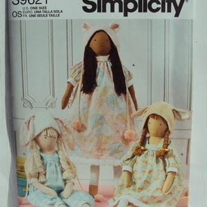 May include: Simplicity sewing pattern number S9621 for making three bunny dolls. The dolls are wearing dresses and overalls. The pattern is for one size.