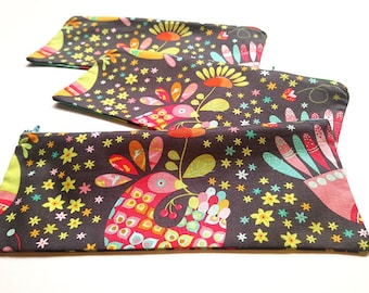 May include: Three zippered pouches with a dark brown background and a colorful pattern of stylized birds, flowers, and stars.