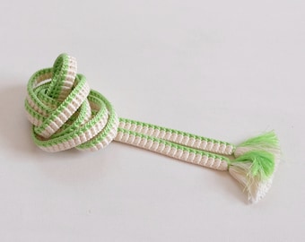 May include: A white and green cord with tassels, tied in a knot. The cord is made of a woven material and has a subtle striped pattern.