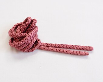 May include: A pair of pink shoelaces, tied in a knot, against a white background.
