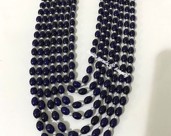 May include: A multi-strand necklace with dark blue oval beads and white pearl beads. The necklace has a gold clasp with blue and white stones.