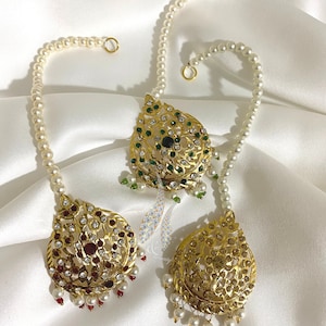 May include: Three gold-tone headpieces with pearl chains. The headpieces are decorated with intricate designs and colorful gemstones. One headpiece has green gemstones, one has red gemstones, and one has clear gemstones.