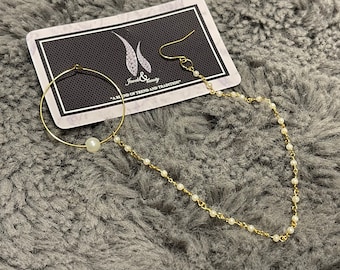 May include: A gold nose ring with a pearl charm and a delicate chain with pearl accents. The nose ring is displayed on a black card with the text "Jewels & Beauty - A Blend of Trend and Tradition".