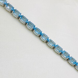 May include: A silver bracelet with oval-shaped blue topaz gemstones.