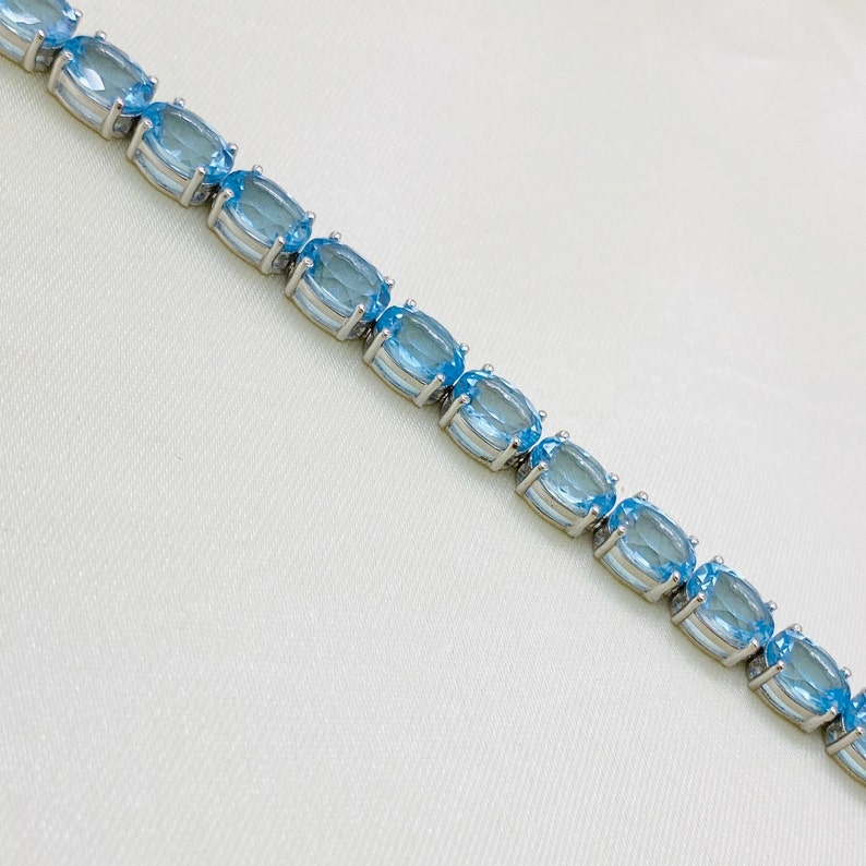 May include: A silver bracelet with oval-shaped blue topaz gemstones.