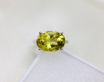 May include: A silver ring with a large, oval-shaped, yellow citrine gemstone.