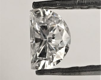 May include: A clear, faceted, half-moon shaped diamond held by tweezers.
