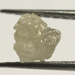 May include: A rough, white, diamond crystal with a slightly cloudy appearance.