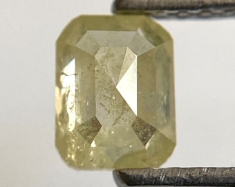 Puede incluir: Un diamante de talla esmeralda de color amarillo claro con inclusiones.