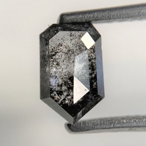 May include: A black emerald cut diamond with inclusions. The diamond is set in a silver setting.