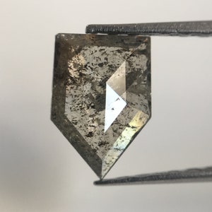 May include: A dark gray, faceted, shield-shaped diamond with a rough, natural finish.