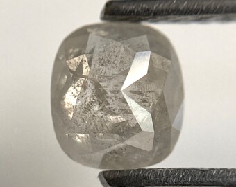 May include: A gray, faceted, cushion-shaped diamond with a rough, unpolished finish.