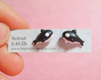May include: A pair of black and white orca earrings. The earrings are made of polymer clay and are handmade by Anh Dao. The earrings are on a white card with the text "Handmade by Anh Dao" and "www.beprettyme.etsy.com".