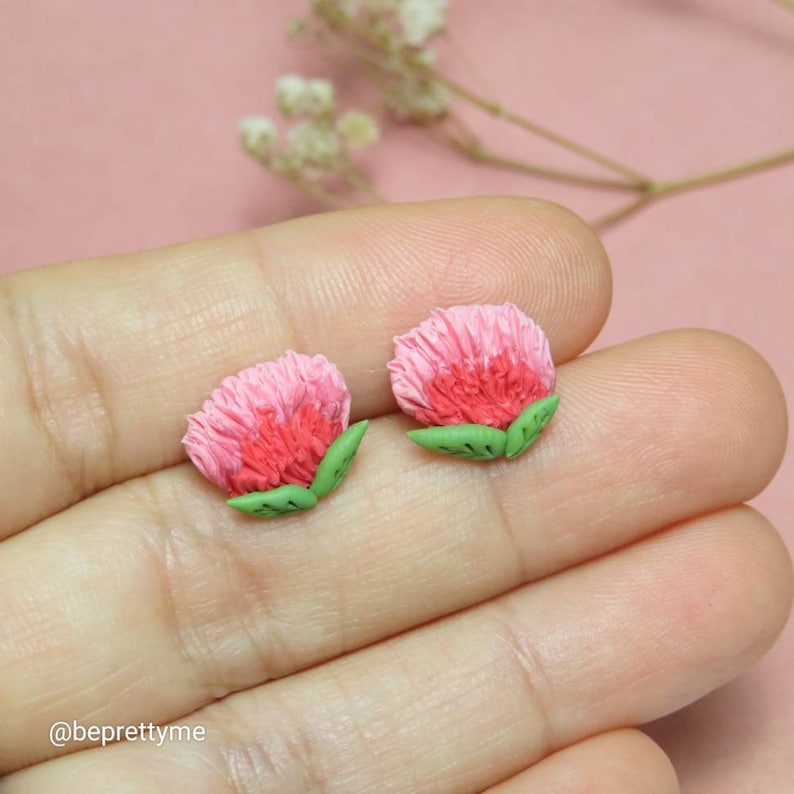 May include: A pair of pink and green flower stud earrings. The flowers are made of polymer clay and have a realistic look.