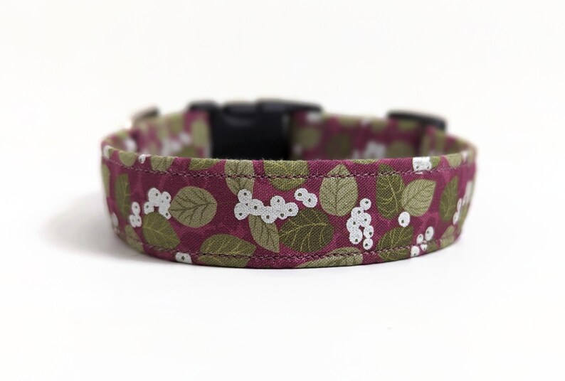May include: A burgundy dog collar with a white and green floral pattern featuring leaves and berries.