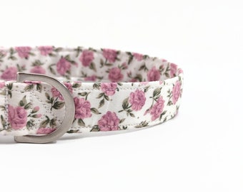 May include: A white dog collar with a pink floral pattern and a silver metal buckle.
