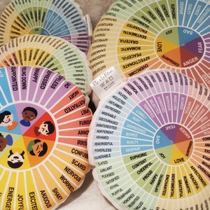 Peut inclure: Un ensemble d'oreillers ronds et color&eacute;s avec une roue des &eacute;motions imprim&eacute;e sur chacun. Les &eacute;motions sont organis&eacute;es en cercle avec des couleurs diff&eacute;rentes pour chaque cat&eacute;gorie. Les oreillers sont faits de tissu doux et sont parfaits pour se blottir ou m&eacute;diter.