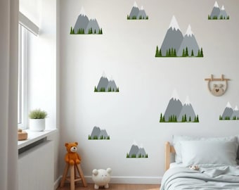 May include: A collection of mountain-shaped wall decals in various sizes. The decals feature gray mountain peaks with white snow caps and green tree lines at the base. The decals are arranged on a white wall in a child's bedroom.