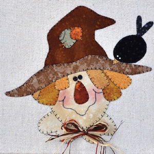 May include: A whimsical patchwork scarecrow with a brown hat, orange and yellow hair, and a friendly face. A small black bird sits on the scarecrow's hat.