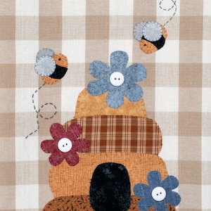 May include: A brown and tan patchwork beehive with a red flower, two blue flowers, and three bees. The beehive is on a brown and white gingham background.