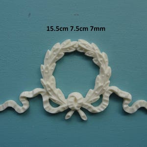 Puede incluir: Moldura decorativa de yeso blanco con un diseño de corona y acentos de cinta. La moldura mide 15,5 cm por 7,5 cm y tiene un grosor de 7 mm.