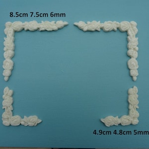 Puede incluir: Cuatro molduras de esquina de plástico blanco con un diseño floral. Las molduras miden 8,5 cm por 7,5 cm por 6 mm y 4,9 cm por 4,8 cm por 5 mm.