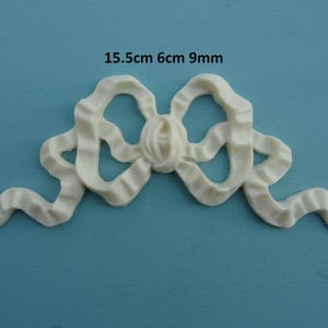 May include: White plastic decorative bow with a 15.5 cm by 6 cm by 9 mm size.