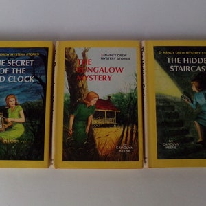 May include: Three vintage Nancy Drew mystery books with yellow spines. The titles are "The Secret of the Old Clock", "The Bungalow Mystery", and "The Hidden Staircase". Each cover features an illustrated scene with a woman.