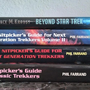 May include: A stack of four paperback books about Star Trek. The top book is titled "Beyond Star Trek" by Lawrence M. Krauss. The next three books are titled "The Nitpicker's Guide for Next Generation Trekkers Volume II", "The Nitpicker's Guide for Next Generation Trekkers", and "The Nitpicker's Guide for Classic Trekkers", all by Phil Farrand.